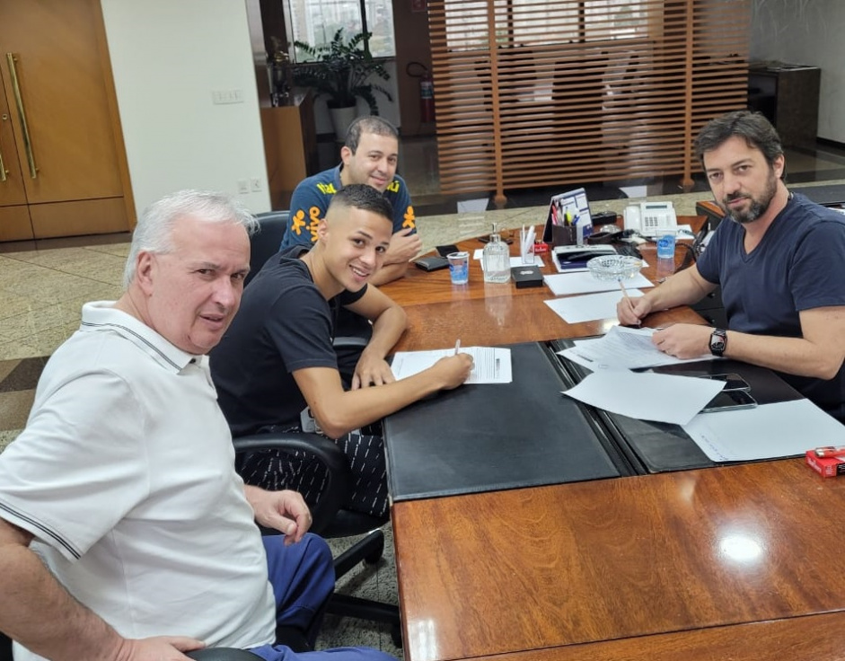Matheus assina o seu novo contrato com o Corinthians na companhia do presidente e do diretor de futebol do clube