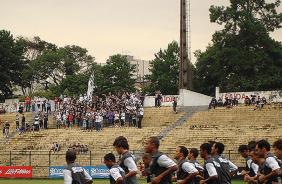 Jogadores do Corinthians correm em volta do gramado enquanto a torcida canta na arquibancada 